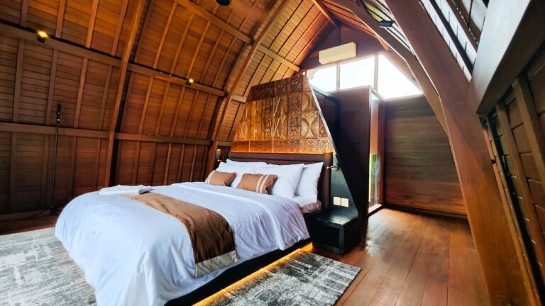 Side angle view of the king bed and seating area in The Mahaloka loft, showing the wooden architecture and natural light.