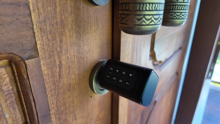 Close-up detail of the modern digital keypad lock installed on the carved wooden entrance door of The Mahaloka lumbung villa.
