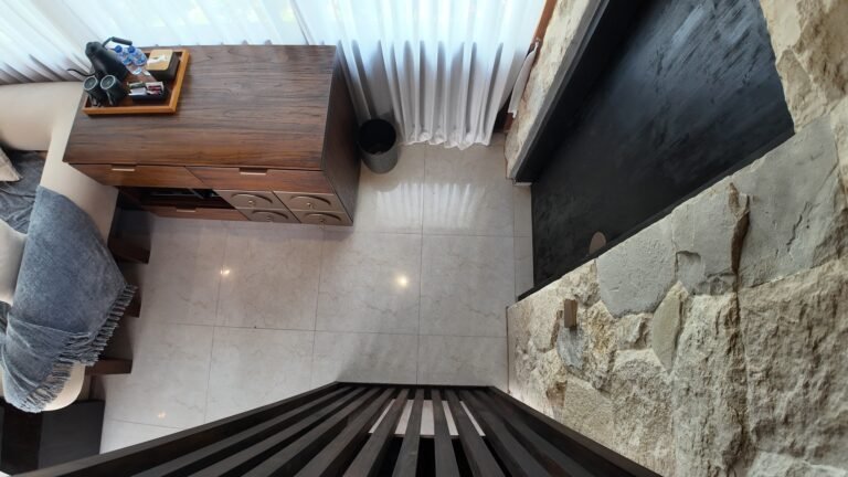 Overhead view from the loft stairs looking down onto the tiled floor, sofa, and refreshment corner of the living area.