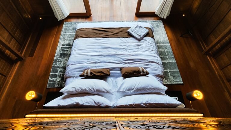 Overhead view looking down onto the neatly made king bed within the warm wood architecture of The Mahaloka lumbung loft.