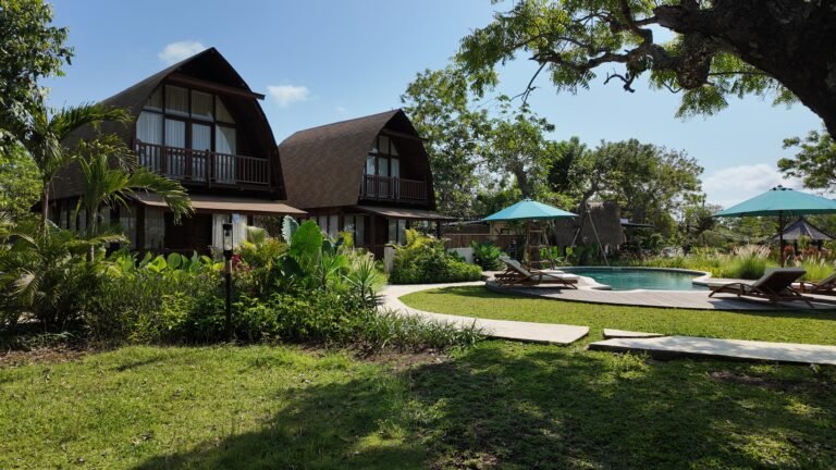 Wide daytime overview of The Mahaloka sanctuary showing both lumbung villas, the shared pool, deck, and green lawn area.
